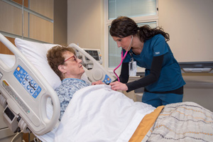 This is a picture of a nurse listening to a elderly lady's breath sounds